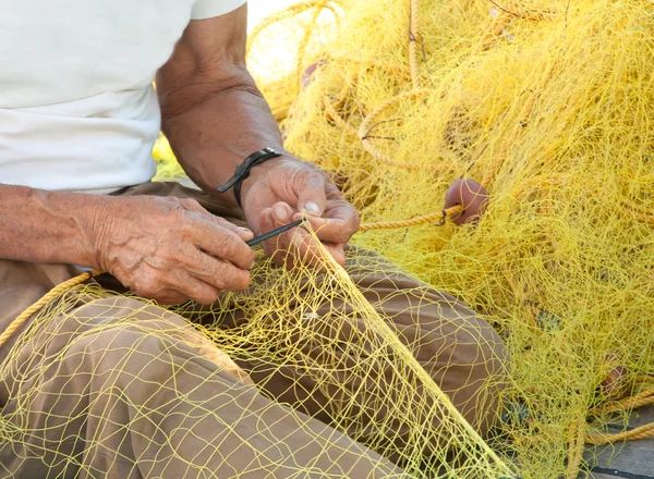Pescador remendando su red de pesca en Grecia —  Fotos de Stock