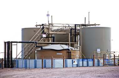 Oil and water storage at an oil well location clipart