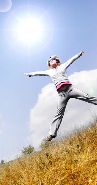 Šťastná žena skákání proti modré obloze — Stock fotografie