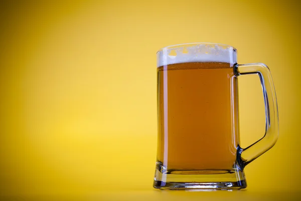 Bicchiere di birra con sfondo giallo — Foto Stock