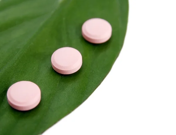 Natürliche Pillen und ein grünes Blatt — Stockfoto