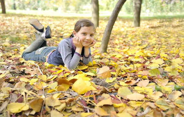 Flickan liggande på hösten lämnar utomhus — Stockfoto