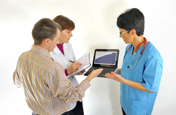 Médico usando computador e revisando relatórios médicos — Fotografia de Stock