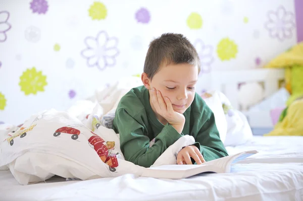 Jonge jongen in zijn bed lezen van een boek — Stockfoto