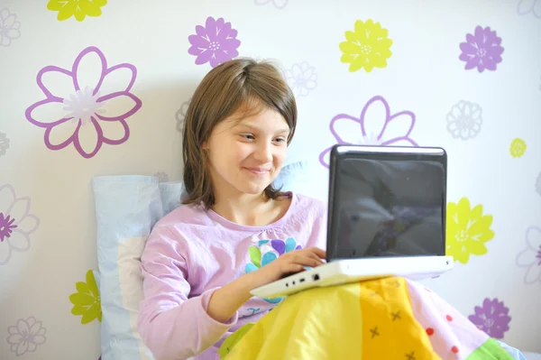 Flicka med laptop i sängen — Stockfoto