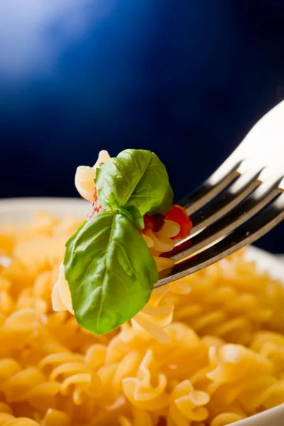 トマトソースと青色の背景にバジルのパスタ — ストック写真