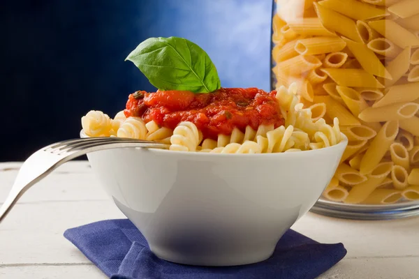 Pasta met tomatensaus op blauwe achtergrond — Stockfoto