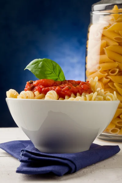 Těstoviny s rajčatovou omáčkou na modrém pozadí — Stock fotografie
