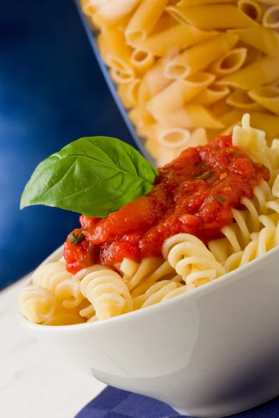 Nudeln mit Tomatensauce und Basilikum auf blauem Hintergrund — Stockfoto