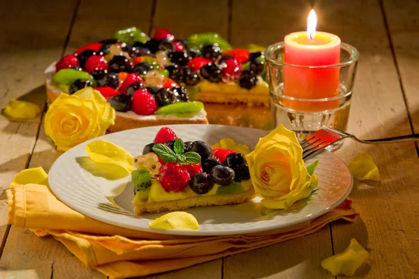 Пиріг з фруктами та пелюстками, освітлений свічковим світлом — стокове фото