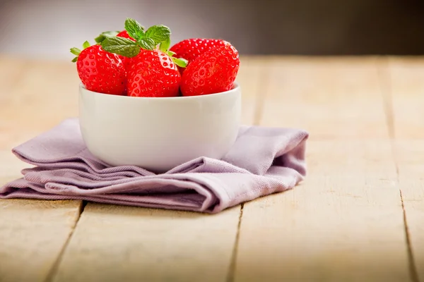 草莓与紫餐巾的木桌上 — 图库照片