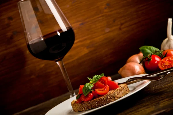 Aperitivo Bruschetta com vinho tinto na mesa de madeira — Fotografia de Stock
