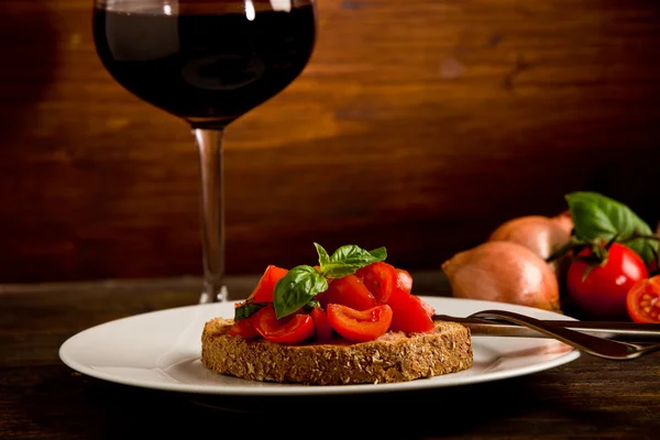 Bruschetta appetizer with red wine on wooden table — Stock Photo, Image