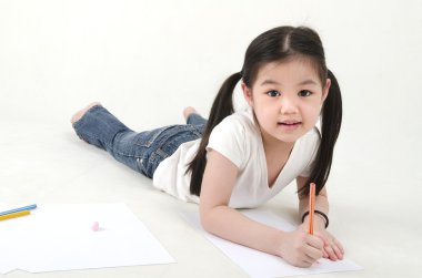 Little Asian girl drawing, lying on floo clipart
