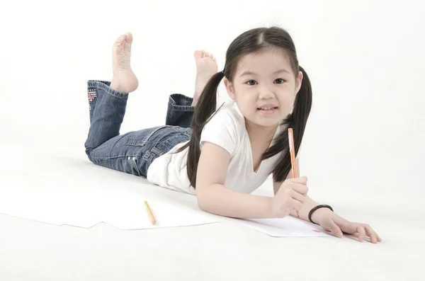 Маленькая азиатка рисует, лежит на полу — стоковое фото