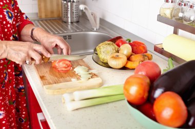 Senior woman's hands cutting vegetables clipart