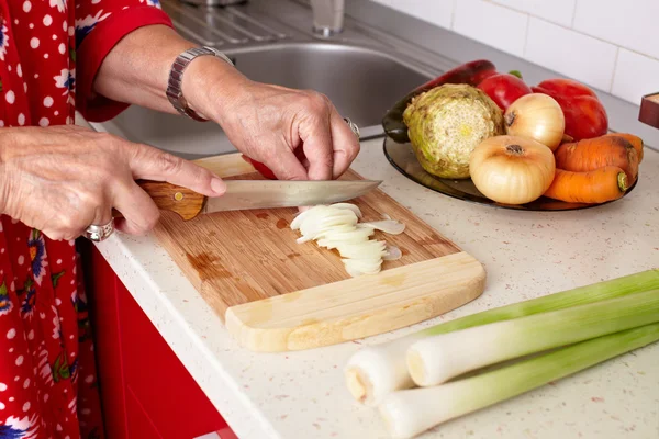 Mãos de mulher sênior cortando legumes — Fotografia de Stock