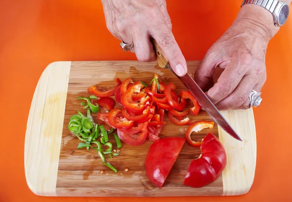 Äldre kvinnas händer skära grönsaker — Stockfoto