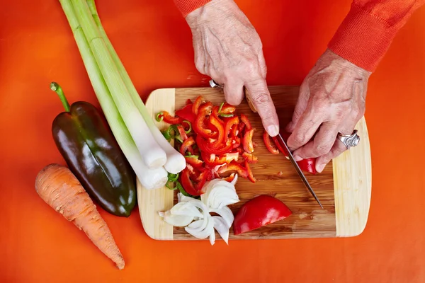 Mãos de mulher sênior cortando legumes — Fotografia de Stock