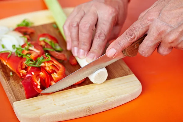 Mani di donna anziana che tagliano verdure — Foto Stock