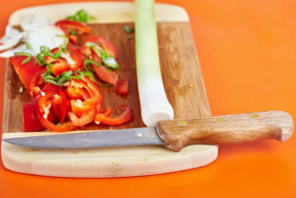 Sliced vegetables and knife on a wooden board — Stock Photo, Image