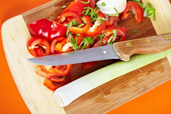 Bir ahşap tahta üzerine dilimlenmiş sebzeler ve bıçak — Stok fotoğraf