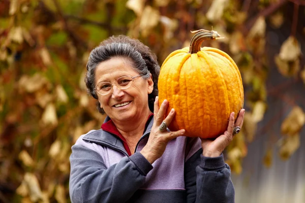 Old woman holding large pumpkin — Stock Photo, Image