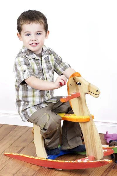 Menino montando um cavalo de balanço — Fotografia de Stock
