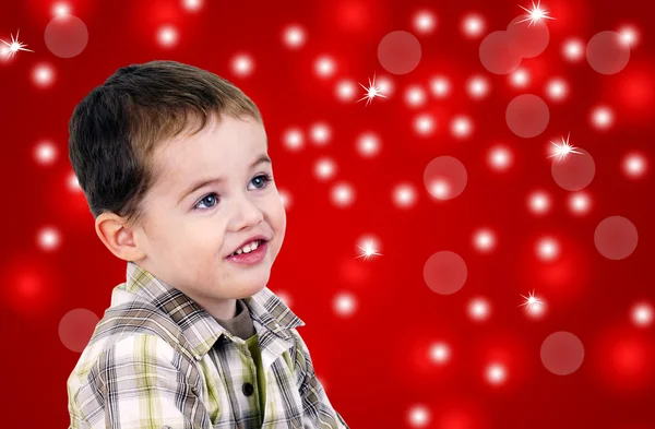 Söt liten pojke på röd bakgrund med ljus — Stockfoto