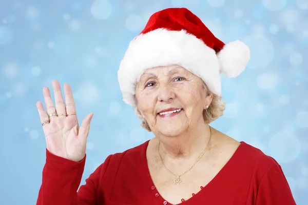 Бабушка в рождественской шляпе машет голубой — стоковое фото