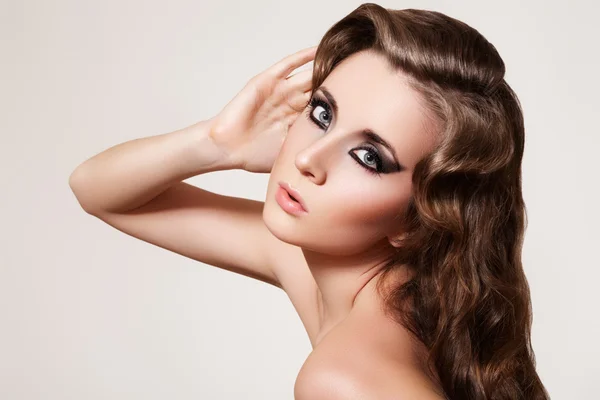 Vacker kvinna modell med glansig lockig frisyr och mörkt sotade ögon — Stockfoto
