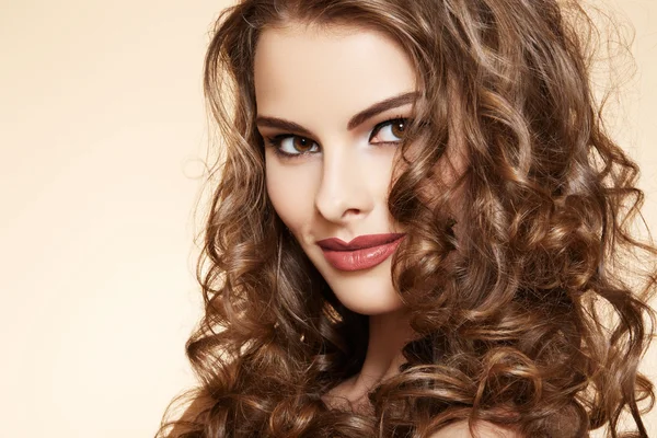 Mooie model met glanzende volume krullend haar. pin-up stijl op beige achtergrond — Stockfoto