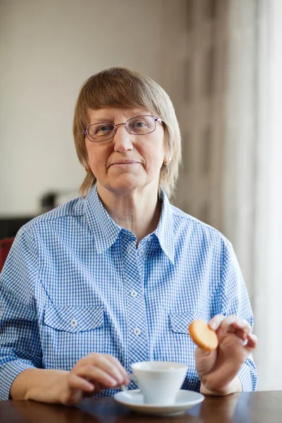 Senior mulher tomando café com biscoito — Fotografia de Stock