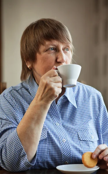 Mujer mayor tomando café y galletas —  Fotos de Stock