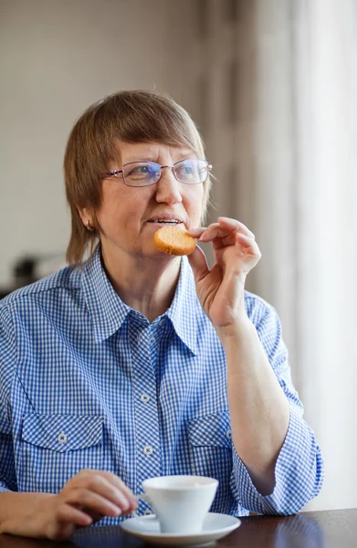 Mujer mayor tomando café con galletas —  Fotos de Stock