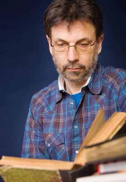 Mature man in glasses reads old book — Stock Photo, Image