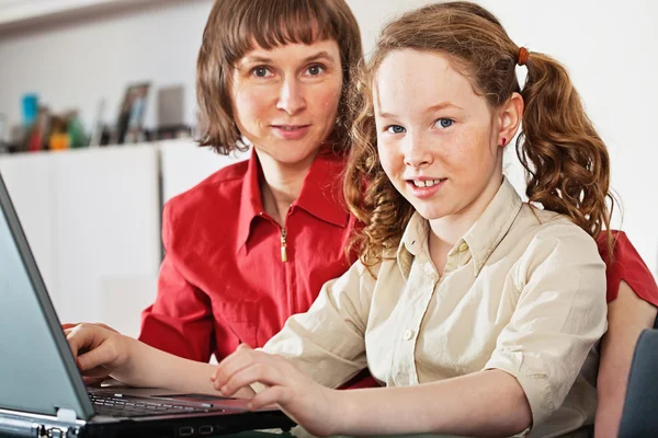 Meisje en haar moeder met laptop thuis — Stockfoto