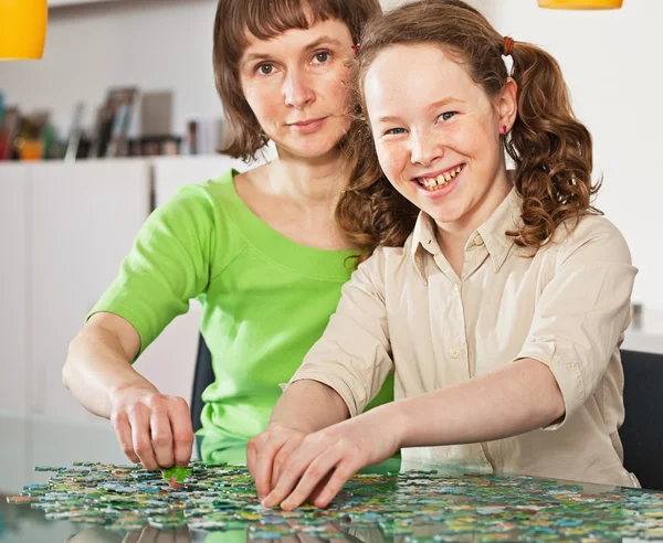 ティーンエイ ジャーの女の子が彼女の母とのジグソー パズルを組み立てる — ストック写真