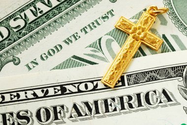 A golden cross on the dollar bills concept of In God We Trust clipart