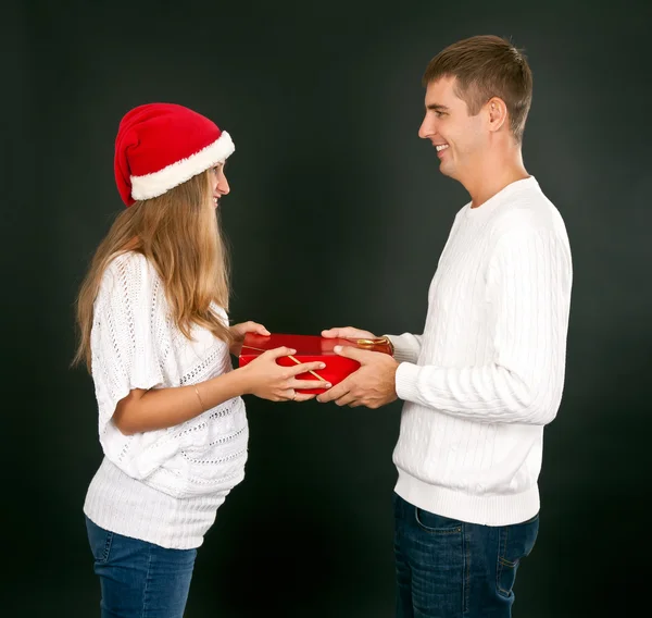 Мужчина дарит подарок беременной девушке в шляпе Санты — стоковое фото