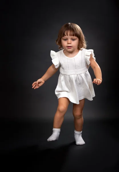 De eerste stappen van een klein meisje op een zwarte achtergrond. — Stockfoto