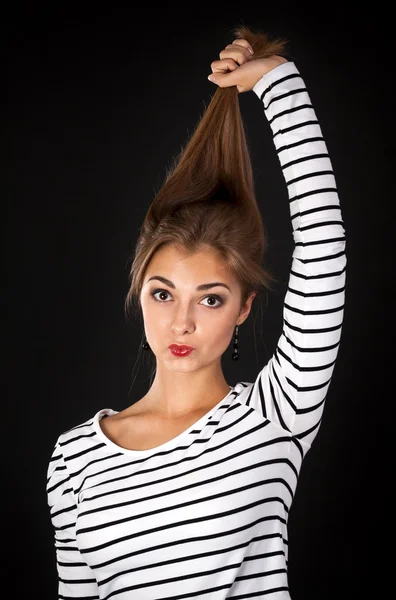 Hermosa chica en un vestido a rayas tira de su cabello —  Fotos de Stock