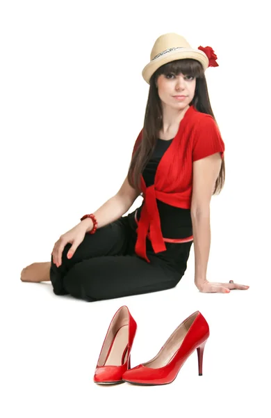 Szép lány, a háttérben egy pár piros női cipő. — Stock Fotó