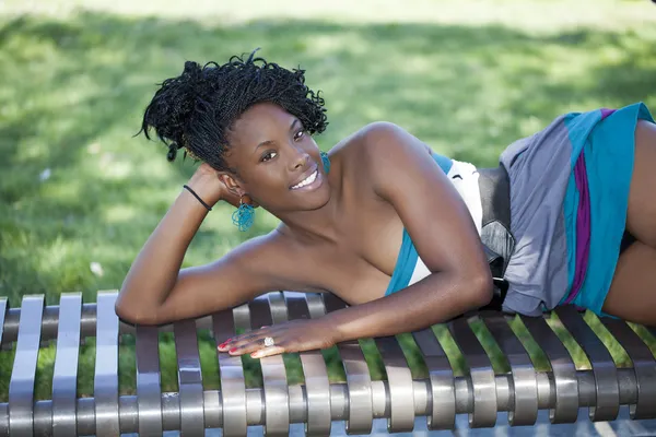 Atraente jovem mulher negra reclinado no banco — Fotografia de Stock