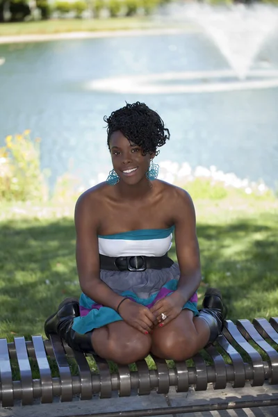 Młoda atrakcyjna kobieta czarny na zewnątrz siedząc na ławce — Zdjęcie stockowe