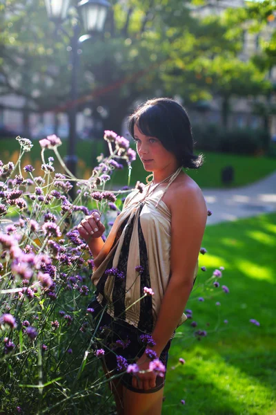 Model in park met violette bloemen — Stockfoto