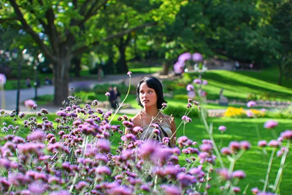 Model in park met violette bloemen — Stockfoto