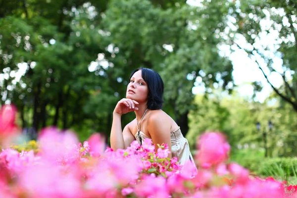 Krásná dívka v parku s růžovými květy — Stock fotografie