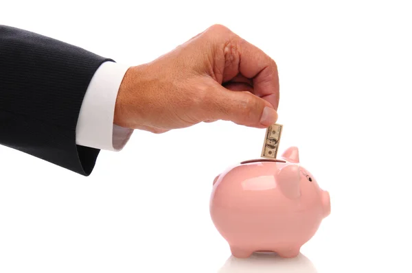 Biznesmen oddanie pieniędzy do piggy bank — Zdjęcie stockowe