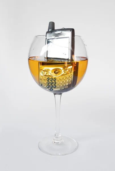 Téléphone portable dans un verre de vin blanc — Photo